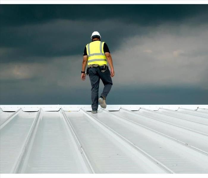 Construction engineer wearing safety uniform inspecting metal roofing work for roof industrial 