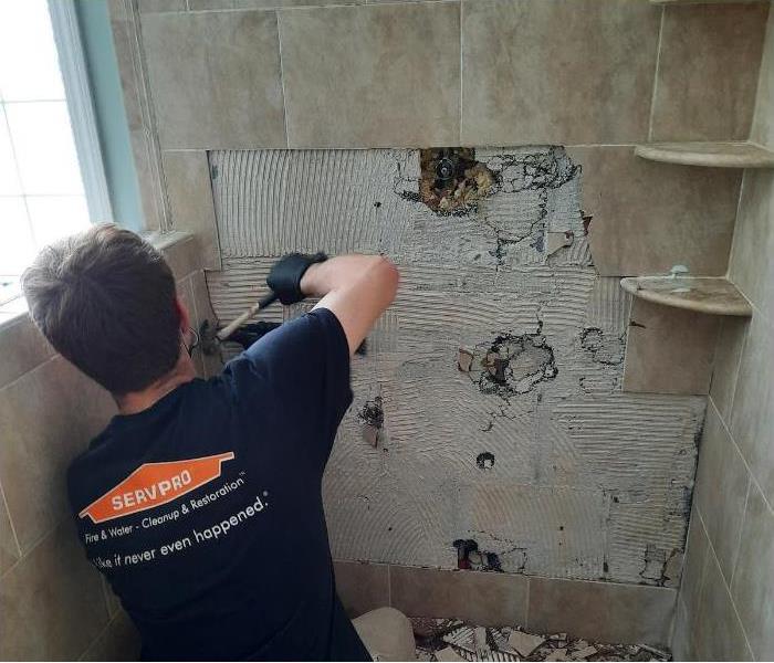 Technician removing tile in a mold damaged bathroom